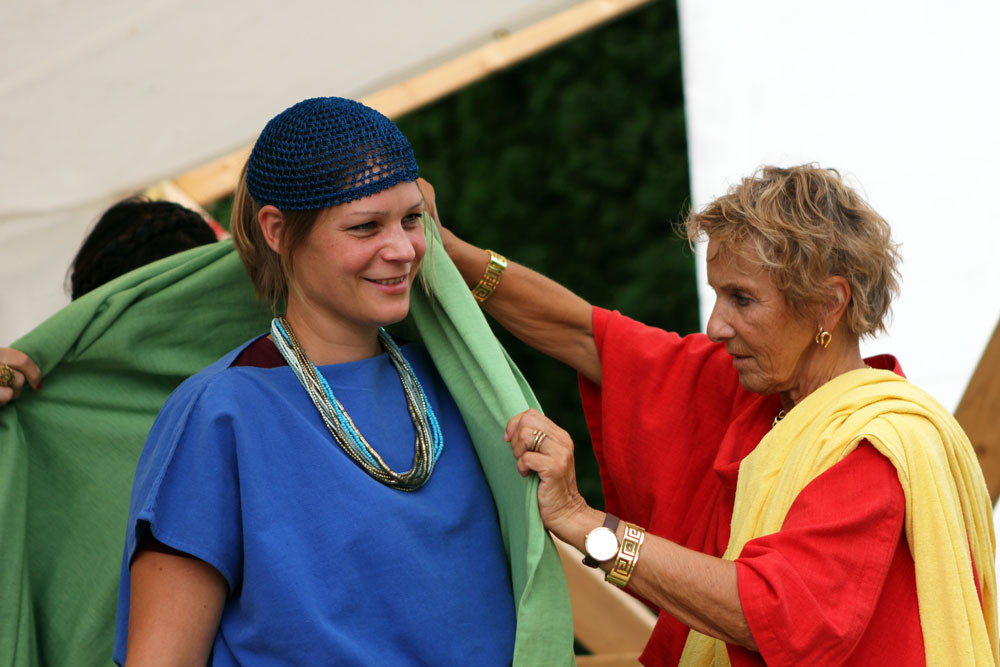 Frau hilft Jugendlicher beim Einkleiden (beide in r&ouml;mischem Gewand)