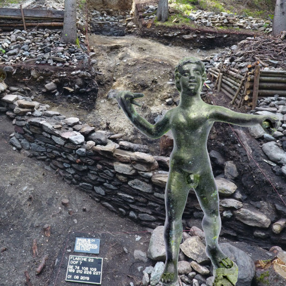 Zinnstatuette vor Ausgrabungsstätte