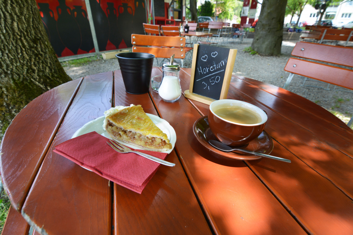 Tisch im Garten der Taberna, gedeckt mit Apfelkuchen und Tasse Kaffee