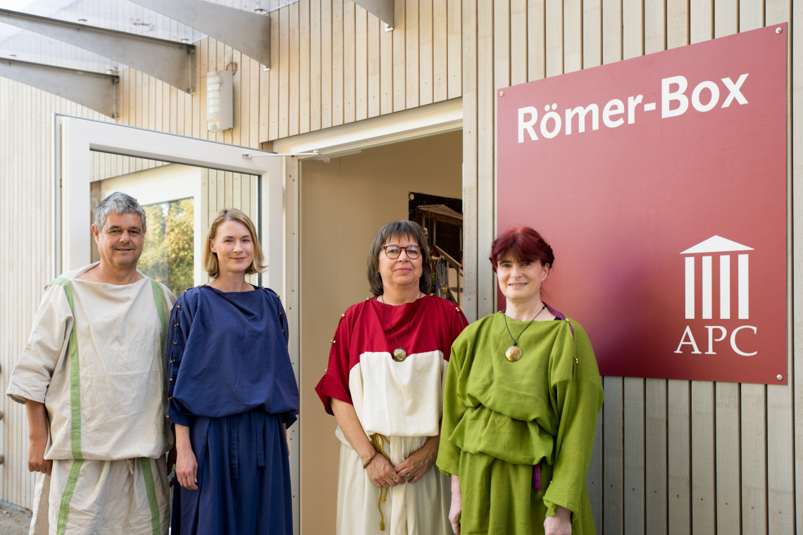 Vier Personen in römischem Gewand vor einer geöffneten Tür