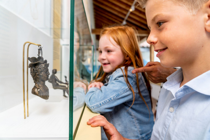 Zwei Kinder bestaunen Ausstellungsgegenstände in einer Vitrine