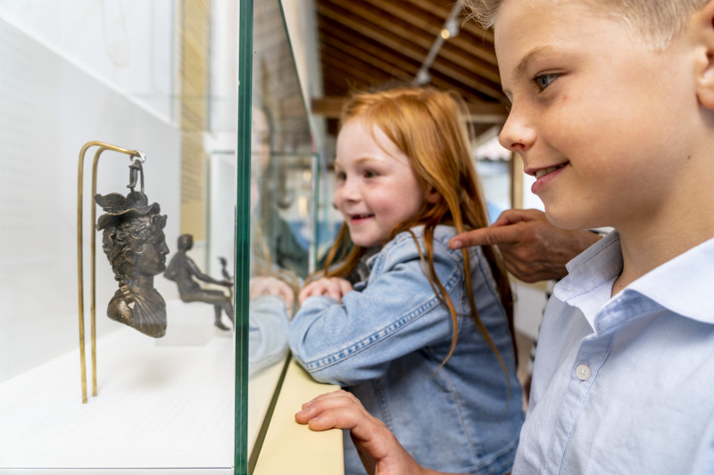 Zwei Kinder bestaunen Ausstellungsst&uuml;cke in einer Vitrine