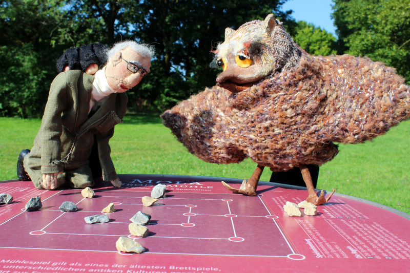 Handpuppen Mann und Uhu auf Spieltisch &quot;Mühle&quot; im Parkgelände