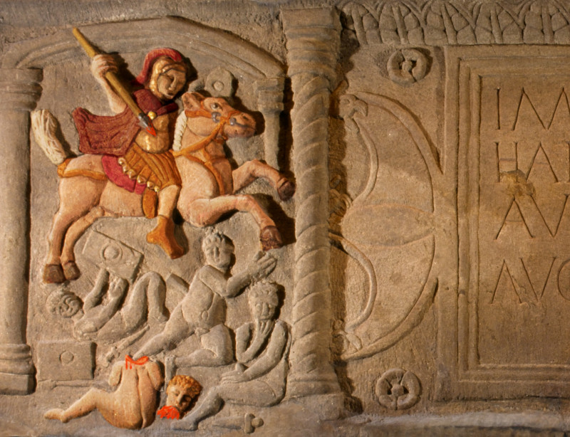 In Stein gemei&szlig;elte Darstellung eines Soldaten, der mit einer Lanze Kinder attackiert und enthauptet